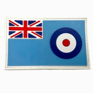 Può includere: Una toppa blu e bianca con un cerchio rosso al centro. La toppa ha un bordo bianco e un'Union Jack nell'angolo in alto a sinistra.