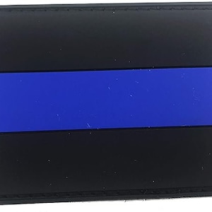 Peut inclure: Un écusson noir et bleu avec une ligne bleue fine. L'écusson est fait d'un matériau ressemblant à du caoutchouc et a une bordure cousue.