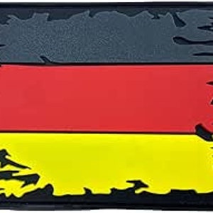 May include: A distressed fabric patch featuring the colours of the German flag: black, red and yellow.
