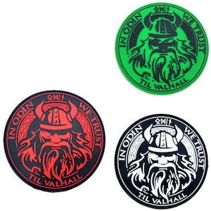 Könnte beinhalten: Drei runde Patches mit einem Schwarzweißbild eines Wikingers mit einem gehörnten Helm. Die Patches haben einen grünen, roten und schwarzen Hintergrund mit dem Text "In Odin We Trust" und "Til Valhalla" in einem Kreis um das Bild.