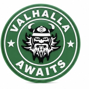 May include: A circular green patch featuring a white border and the text VALHALLA AWAITS in white capital letters. In the centre, a black and white graphic depicts a stylised bearded warrior wearing a horned helmet, flanked by two white stars.