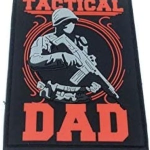 Peut inclure: Patch noir et rouge avec la silhouette d'une personne tenant un fusil. Le texte "Tactical Dad" est imprimé en rouge.