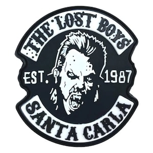 May include: Black and white patch with the text "The Lost Boys Est. 1987 Santa Carla" and a graphic of a vampire with a mohawk.