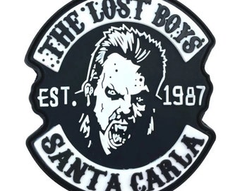 May include: Black and white patch with the text "The Lost Boys Est. 1987 Santa Carla" and a graphic of a vampire with a mohawk.