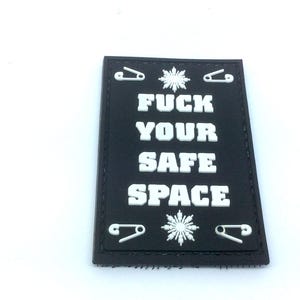 May include: A rectangular black patch featuring the white text FUCK YOUR SAFE SPACE in a bold font. The design includes a white snowflake icon above and below the text, with four white safety pin icons positioned in the corners of the patch.