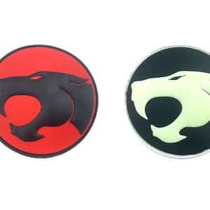 Puede incluir: Dos parches redondos con el logotipo de ThunderCats. Un parche es rojo con una cabeza de pantera negra, el otro es negro con una cabeza de pantera blanca.