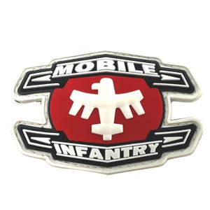 Pode incluir: Patch bordado branco e preto com um círculo vermelho no centro. O círculo apresenta uma águia estilizada branca. O texto "MOBILE INFANTRY" está escrito em letras brancas sobre fundo preto.
