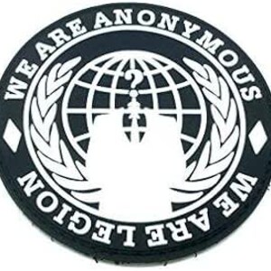 May include: Black and white embroidered patch with the text "We Are Anonymous We Are Legion" surrounding a globe with a question mark and a stylized figure of a person wearing a Guy Fawkes mask.