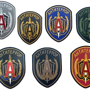 Op de afbeelding: Een verzameling van acht patches met het woord "ANTITERROR" in het Cyrillisch schrift. Elke patch heeft een schildontwerp met een zwaard, de letter "A" en laurierbladeren, in verschillende kleurenschema's.