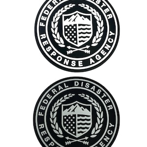 Op de afbeelding: Twee zwart-witte cirkelvormige emblemen met de tekst "FEDERAL DISASTER RESPONSE AGENCY" rond een centraal ontwerp. Het ontwerp bevat een schild met een berg, sterren en strepen, en gekruiste pijlen.