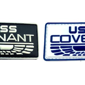 Peut inclure: Deux patchs brodés avec le texte "USCSS COVENANT" en lettres blanches sur fond noir et en lettres blanches sur fond blanc avec des accents bleus.