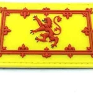 Op de afbeelding: Een gele stoffen patch met een rode leeuw in de rug in het midden. De leeuw wordt omringd door een rode rand met decoratieve versieringen. De patch heeft een gele achtergrond en een rode rand.