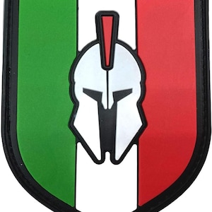 May include: A green, white and red shield-shaped patch with a black outline. A white Spartan helmet with a red crest is centred on the patch.