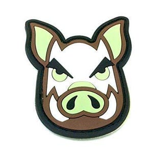 May include: A rubberised patch featuring a stylised, angry boar head. The design uses a colour palette of white, brown, black, and pale green. The boar has pointed ears, a prominent snout, and sharp, angled eyebrows, all outlined in thick black.