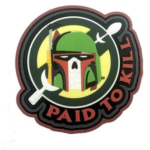 Peut inclure: Un écusson rond rouge, noir et vert avec un réticule blanc et le texte "Paid to Kill" en cercle autour d'une image de la tête de Boba Fett.