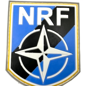 May include: A blue and black patch with a white compass star and the letters "NRF" in white.