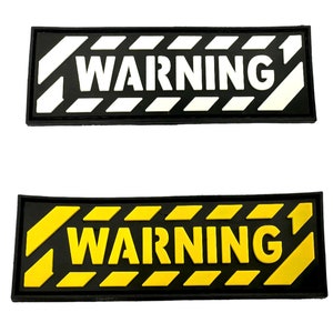 May include: Two black rectangular warning signs with white and yellow diagonal stripes. The top sign has white text that reads "WARNING" and the bottom sign has yellow text that reads "WARNING".
