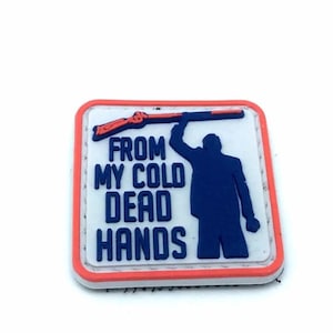 Peut inclure: Un écusson brodé blanc, rouge et bleu avec la silhouette d'une personne tenant un fusil et le texte "From My Cold Dead Hands".