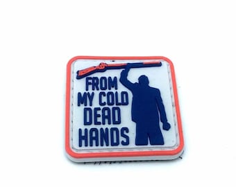 May include: A white, red, and blue embroidered patch with a silhouette of a person holding a rifle and the text "From My Cold Dead Hands".