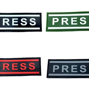 Peut inclure: Quatre patchs rectangulaires avec le mot "PRESS" imprimé en blanc sur fond noir, blanc sur fond vert, rouge sur fond noir et gris sur fond noir.