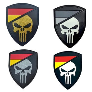 May include: Four black and white skull patches with a red, yellow and black German flag design. The skull patches are in the shape of a shield.