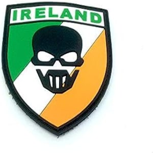 Puede incluir: Una calavera negra con barba blanca y ojos verdes está centrada en un parche con forma de escudo. El escudo está dividido en tres secciones: verde, blanco y naranja. La palabra "IRLANDA" está impresa en letras negras en la parte superior del parche.