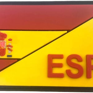 Könnte beinhalten: Ein rechteckiger Aufnäher mit dem Design der spanischen Flagge. Der obere Teil ist rot, der untere Teil gelb mit den Buchstaben "ESP" in Rot. Das spanische Wappen befindet sich auf der linken Seite.