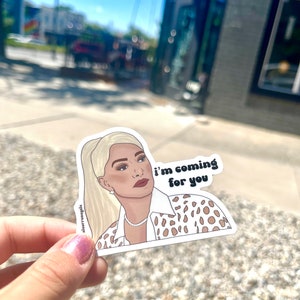 Puede incluir: Una pegatina con una ilustración de dibujos animados de una mujer con cabello rubio que lleva una camisa de estampado de leopardo blanco y marrón. El texto "i'm coming for you" está escrito en una fuente retro.