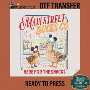 May include: DTF transfer featuring two ducks wearing Mickey Mouse hats, with the text "Main Street Ducks Co." and "Here for the Snacks." The design includes a colorful background of buildings and popcorn.