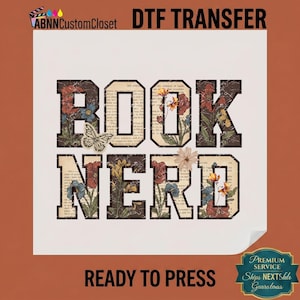 May include: A DTF transfer sheet featuring the text BOOK NERD in large block letters. The letters have a vintage book page background with floral illustrations in red, blue, and yellow, and a butterfly graphic. The text is ready to press.