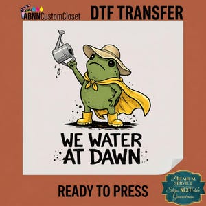 May include: A DTF transfer featuring a green frog wearing a tan sun hat, yellow cape, and yellow boots, holding a silver watering can. The text reads ABNNCustomCloset DTF TRANSFER, WE WATER AT DAWN, and READY TO PRESS, with a PREMIUM SERVICE seal.