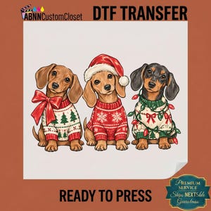 May include: A DTF transfer featuring three dachshunds. The left dog wears a white sweater with green trees and a red bow. The center dog wears a red sweater with white snowflakes and a Santa hat. The right dog wears a white sweater with green lights.