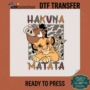 May include: A DTF transfer sheet featuring a cartoon lion cub, a warthog, and a meerkat centered over a gray and white animal print square. The text HAKUNA MATATA is printed in brown block letters above and below the characters on a white background.