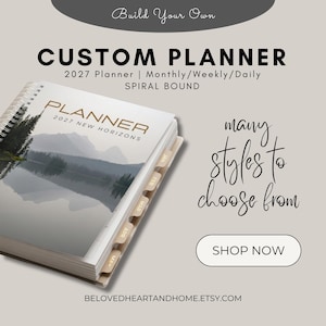 May include: A spiral-bound 2027 custom planner with a landscape cover featuring a lake and mountain scene. The cover text reads PLANNER 2027 NEW HORIZONS. The planner includes monthly tab dividers labeled JAN, FEB, MAR, APR, and MAY along the side.