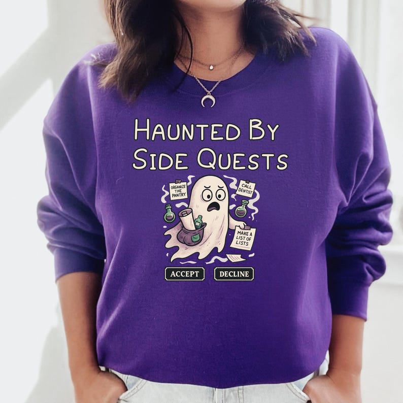 May include: A purple sweatshirt with the phrase "HAUNTED BY SIDE QUESTS" and a cartoon ghost graphic. The ghost holds a scroll and is surrounded by "ORGANIZE THE PANTRY", "CALL DENTIST", and "MAKE A LIST OF LISTS" signs. Below are "ACCEPT" and "DECLINE" buttons.