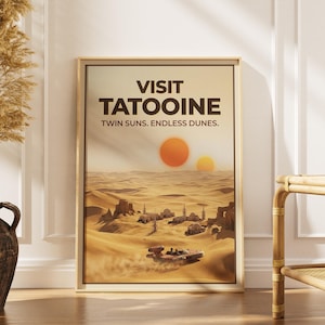 May include: Framed poster with a vintage travel advertisement for Tatooine, featuring twin suns over a desert landscape. The poster reads "VISIT TATOOINE" with the tagline "TWIN SUNS. ENDLESS DUNES."