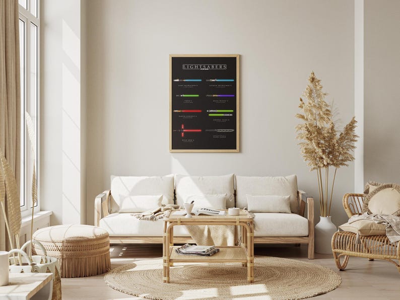 May include: A framed poster showing lightsaber designs on a black background, hanging above a light wood sofa with white cushions. The room is decorated in neutral tones. The poster is in a wooden frame. The room has natural light.
