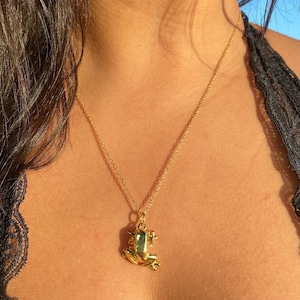 May include: A gold chain necklace with a gold frog pendant.