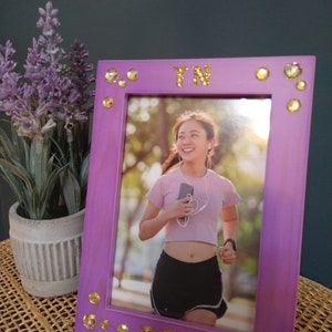 May include: Purple picture frame with gold glitter letters spelling "TN TECH" and rhinestones around the border. A photo of a woman smiling and holding a phone is inside the frame.