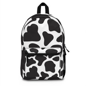 May include: A black and white cow print backpack with a zippered front pocket.