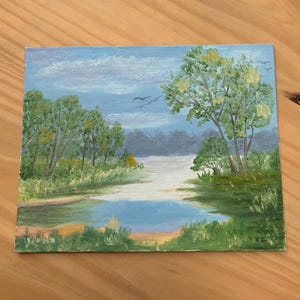 May include: An oil painting depicts a serene landscape with a river winding through lush greenery. The sky is a soft blue with fluffy white clouds and a few birds in flight. The trees are painted in shades of green and yellow.