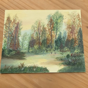 May include: An oil painting depicts a serene landscape with a body of water reflecting the sky. Trees with green, brown, and red foliage line the water's edge. The artwork evokes a sense of tranquility and natural beauty.