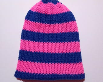 Puede incluir: Un gorro de punto con rayas horizontales en rosa brillante y azul marino. El gorro está hecho de un hilo suave y texturizado y tiene una parte superior redondeada. Este gorro hecho a mano es un accesorio elegante para el clima frío.