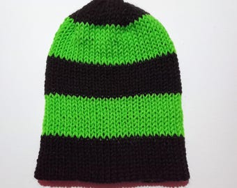 Puede incluir: Un gorro de punto con rayas horizontales negras y verde neón alternas. El gorro está hecho de un material suave y texturizado y está diseñado para ajustarse perfectamente a la cabeza. Es un accesorio vibrante.