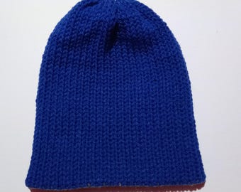 Puede incluir: Un gorro de punto azul liso. El gorro está hecho de un hilo grueso y texturizado, con un diseño simple y clásico. El gorro es de un tono azul vibrante y es un cálido accesorio de invierno.