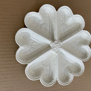 Puede incluir: Plato de servir de cerámica blanca con seis secciones en forma de corazón, cada una con un diseño floral en relieve.