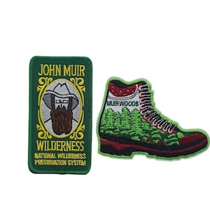 May include: Two embroidered patches, one featuring a portrait of John Muir with the text "John Muir Wilderness National Wilderness Preservation System" and the other a red and green hiking boot with the text "Muirwoods".