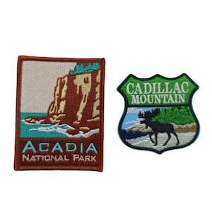 Może przedstawiać: Dwa haftowane naszywki. Pierwsza naszywka jest prostokątna i przedstawia brązową klif z niebieską wodą i tekstem "Acadia National Park". Druga naszywka ma kształt tarczy i przedstawia zielone tło z tekstem "Cadillac Mountain" i czarnym łosiem.