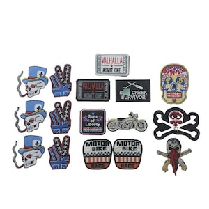 May include: A collection of 13 iron-on patches featuring various designs, including skulls, motorcycles, American flags, and the text "Valhalla", "Sons of Liberty", "Motor Bike", and "SCREEK SURVIVOR".