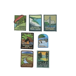 May include: A set of seven embroidered patches featuring various national parks and monuments. The patches are rectangular and feature a variety of colors, including green, blue, brown, and yellow. The patches include the names of the parks and monuments, such as "Grand Portage National Monument", "Sleeping Bear Dunes National Lakeshore", and "Mammoth Cave National Park".